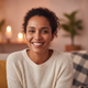 Close-up portrait of a smiling woman, mid-30s, with a relaxed and happy expression, against a blurred background.